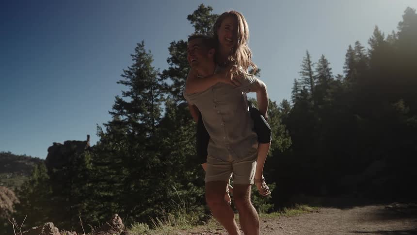 A woman jumps on a mans back as they hike
