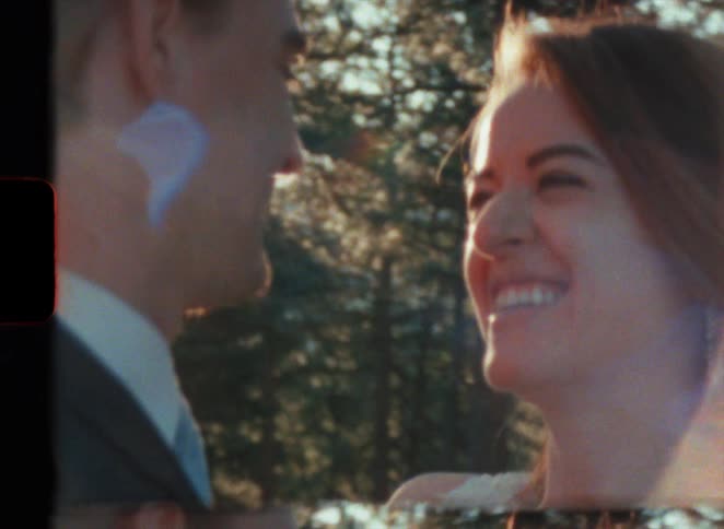 Groom in suit and bride look into each others eyes smiling next to the forest in super 8 film