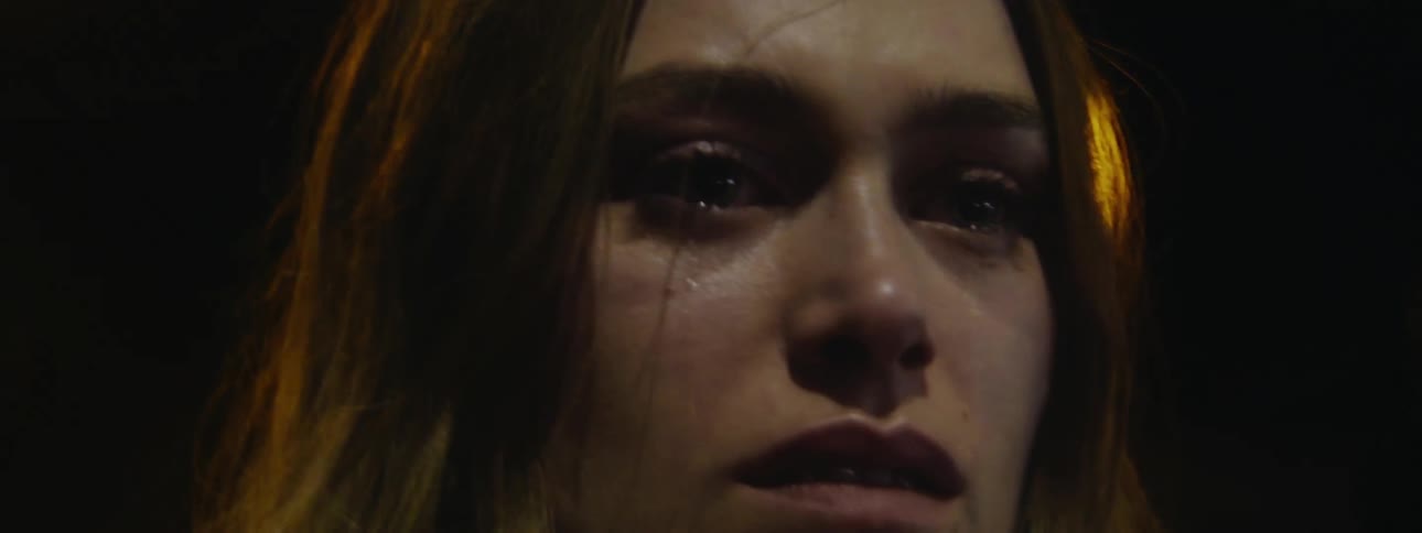 Crying woman with tear drops on her face standing in the middle of the city at night