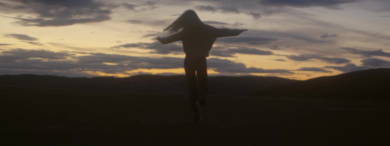 Young woman with open arms spinning around in an open field