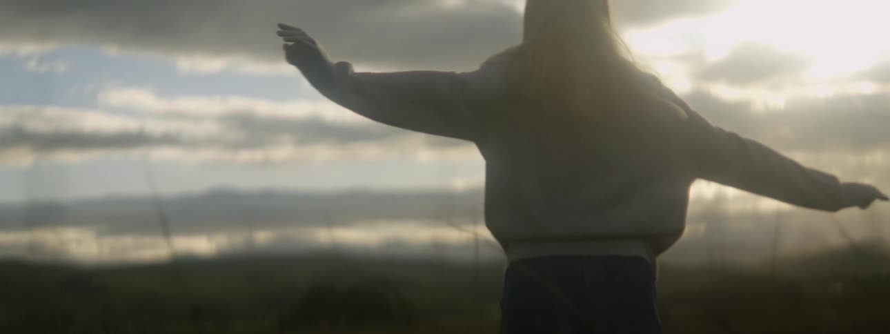 A woman spins in a field with her arms outstretched