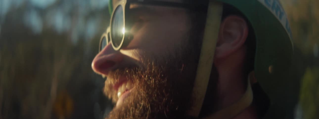 A man smiles while standing outside in a helmet
