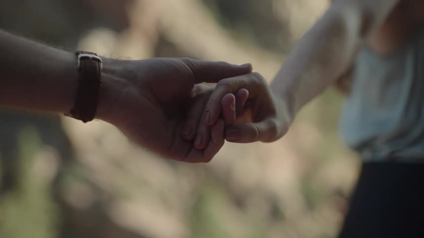 Couple stand still holding hands outdoors