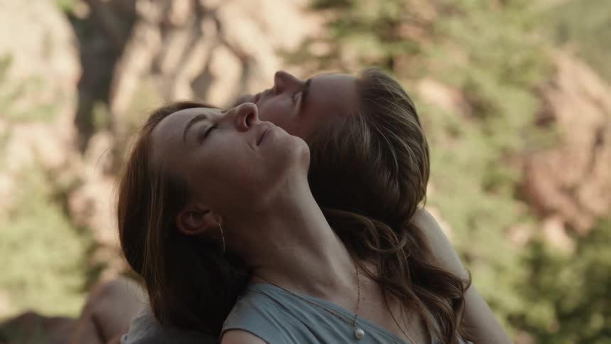 Couple sitting on grass resting outdoors with their heads resting on each others shoulder
