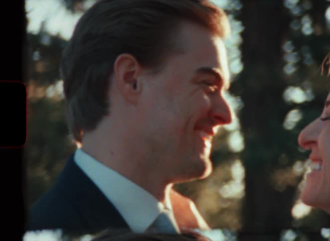 A man in a suit smiles broadly at his wife who smiles enthusiastically back at him in super 8 film