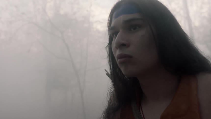 Tribal person looking cautiously around in a smoky wooded area