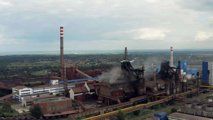Aerial view of smoke rising from a factory near a small Eastern European town