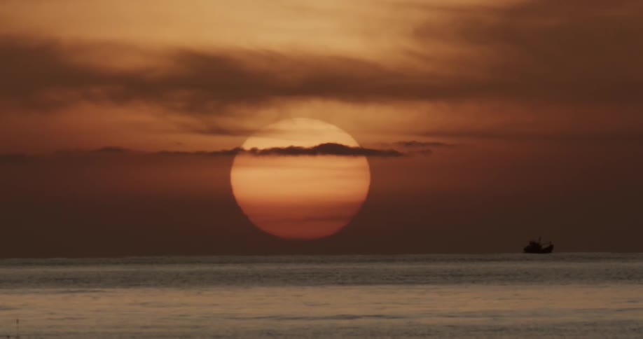 A huge sun rising above the ocean waves