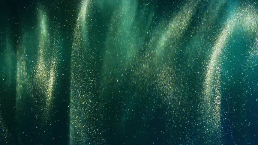Bright green emerald particles rain down in shimmering waves