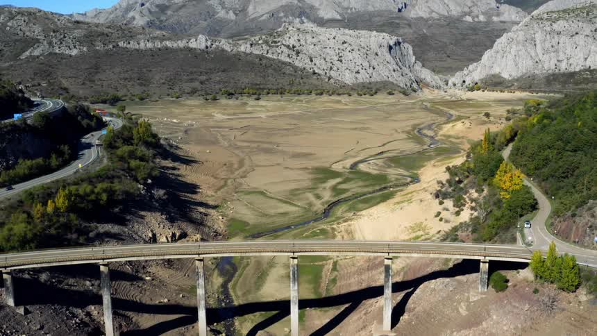 A dry riverbed lies under a tall traffic bridge in the north of Spain
