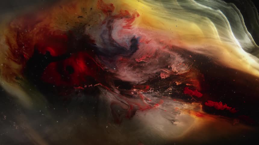 A puddle of multiple paint colors is shown highly magnified while colors and liquid blend into one another