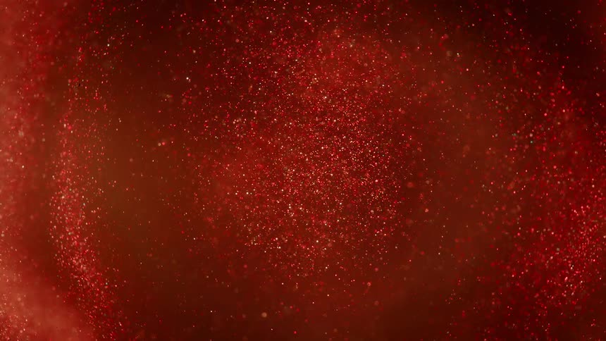 Spinning shimmering bright particles spinningon a concentric pattern on a intense dark red liquid