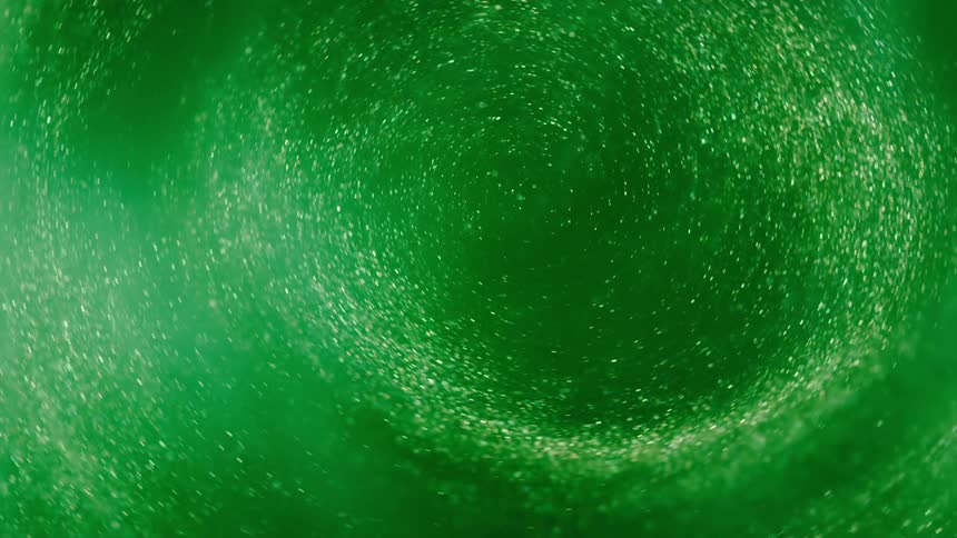 Glitter moves and swirls in a green glowing vortex of anomalous light