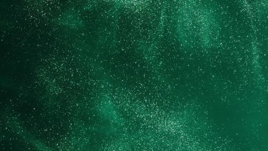 Tiny particles move and glitter in the atmosphere illuminated with green light moving across the darkness