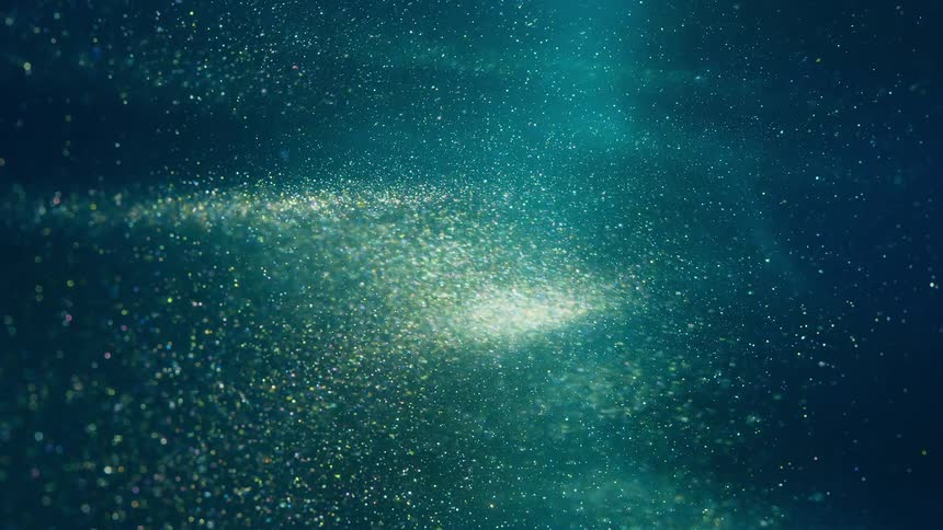 A cloud of glittering and shimmering particles flow through a blue hued expanse