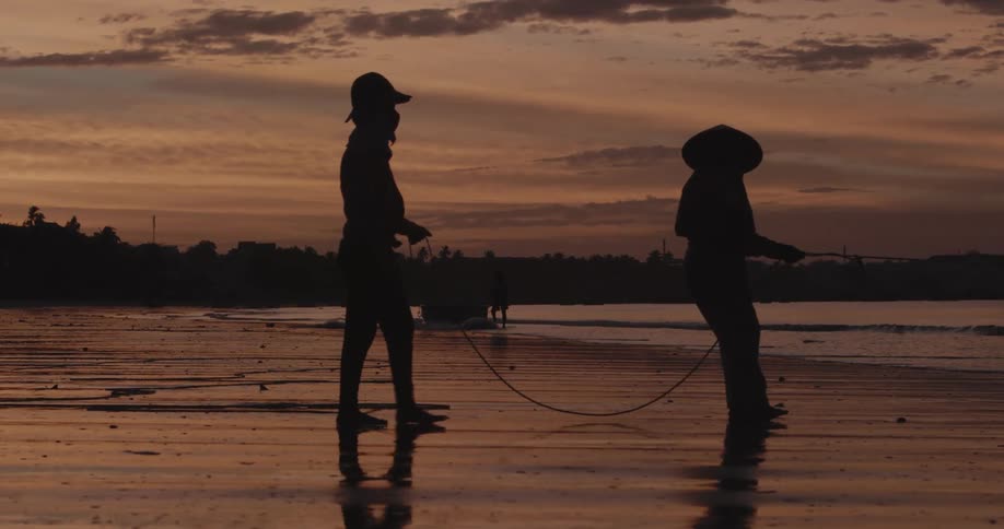Two people on a beach pull on a rope