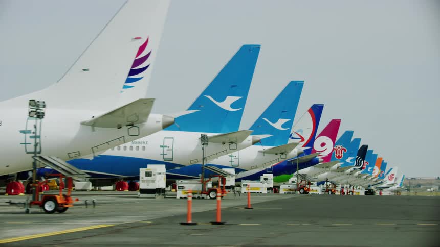 A row of large airplanes lined up in an airfield on a cloudy day