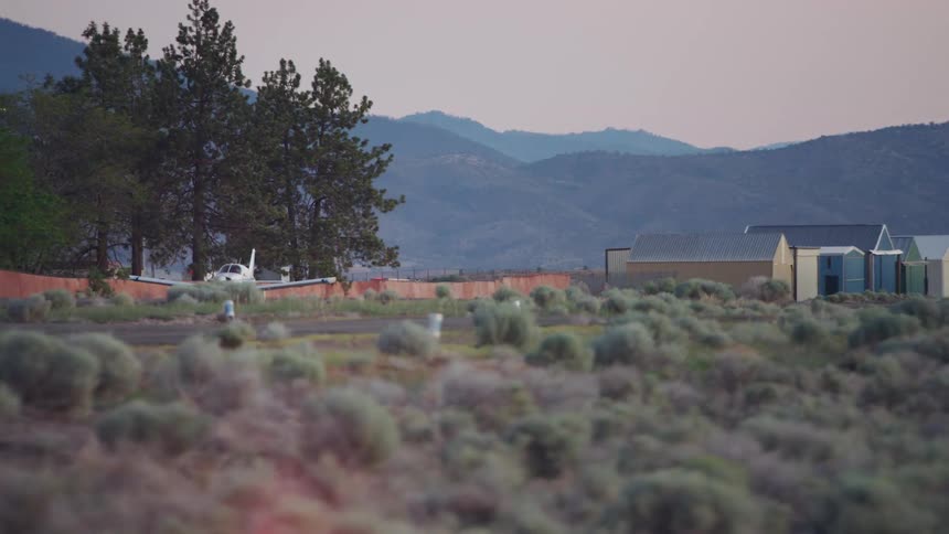 A Piper PA-28 Cherokee taxis towards the runway in preparation for take off at a small airport nestled in the mountains