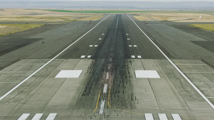 A long runway stretches across open land in this dynamic zoom out shot simulating a landing aircraft