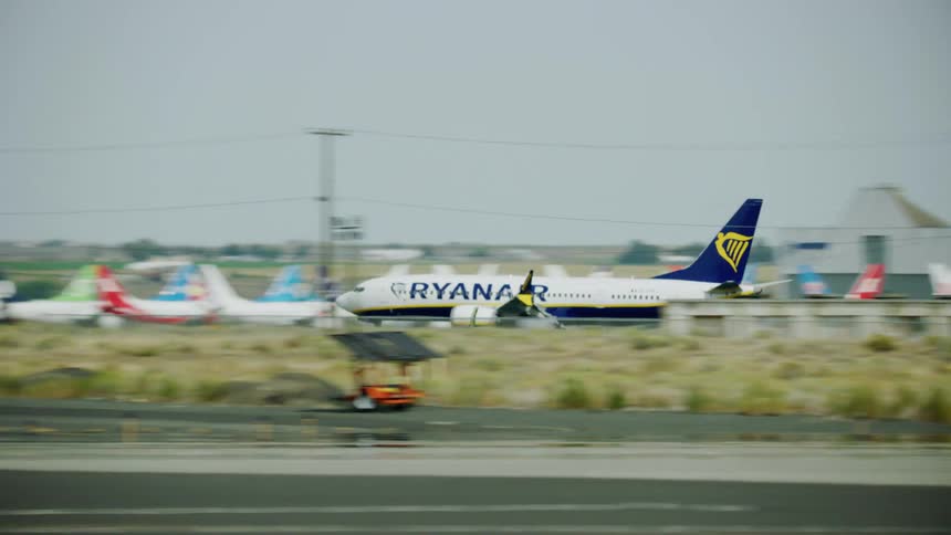 An airplane is coming in for a landing as it flies low over the runway moving by planes parked on the tarmac