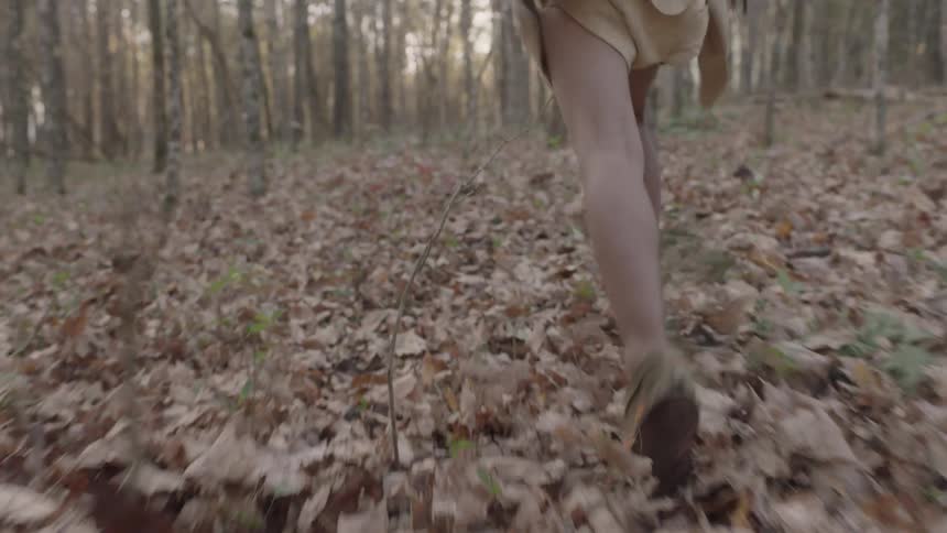 A child runs through leaves in the woods
