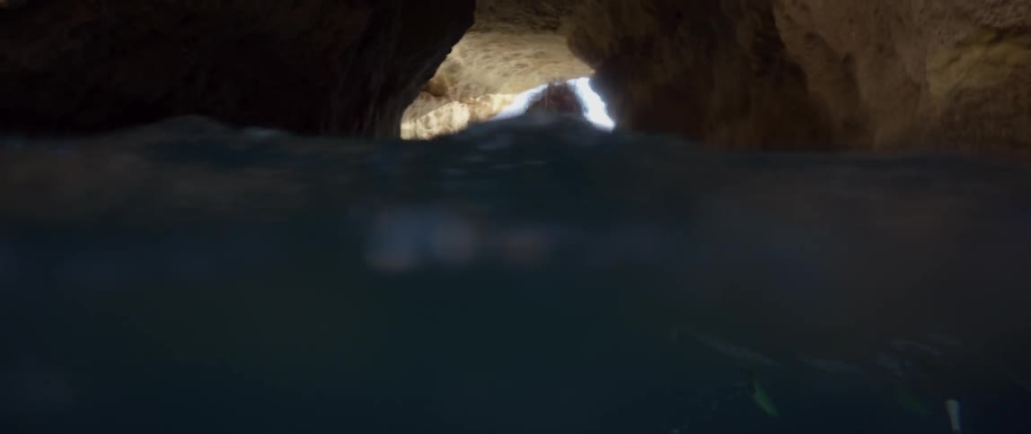 A person is paddling on a surfboard in a water filled cave
