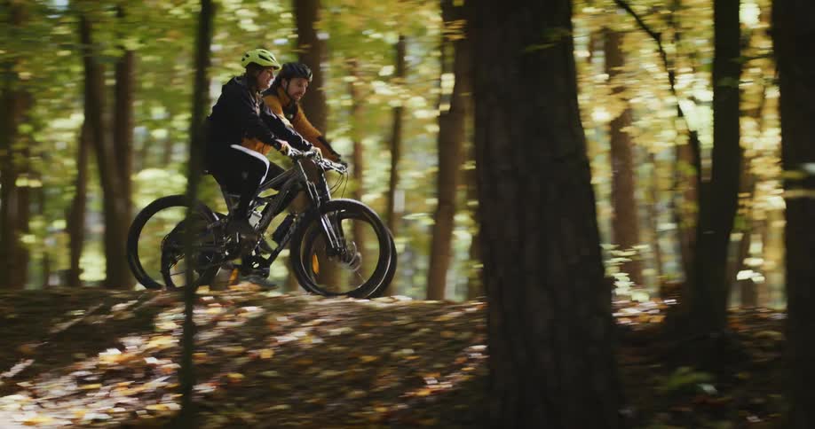 Two older adults are riding there bike down a trail outside