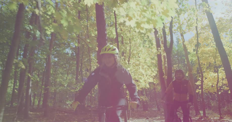 A man and woman bike through a forest