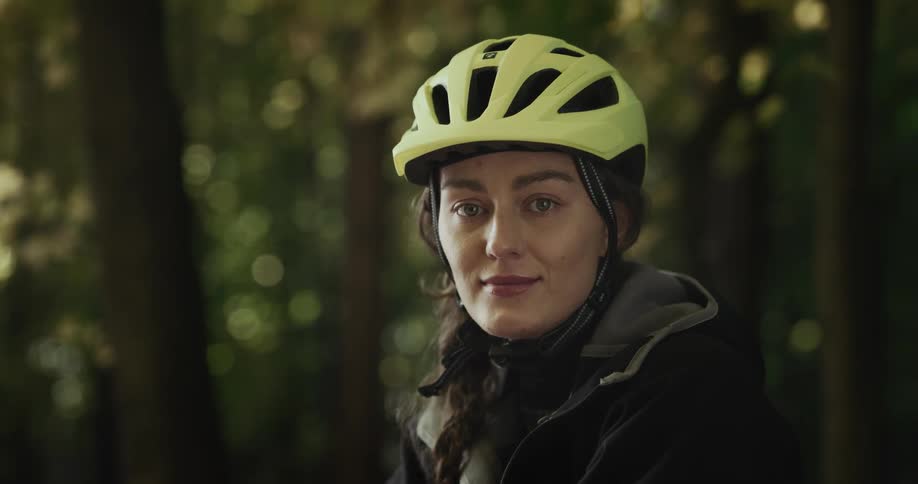 A woman wearing a bike helmet poses in a dense forest