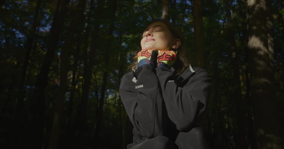 Woman sitting on the ground in the forest at morning takes out a bike helmet to relax