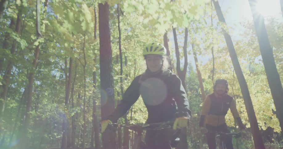 A woman looks back at her partner while they ride bicycles through the forest