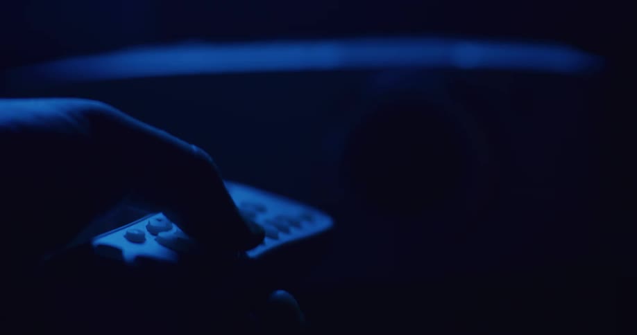 A person changes the channel on a television using the remote