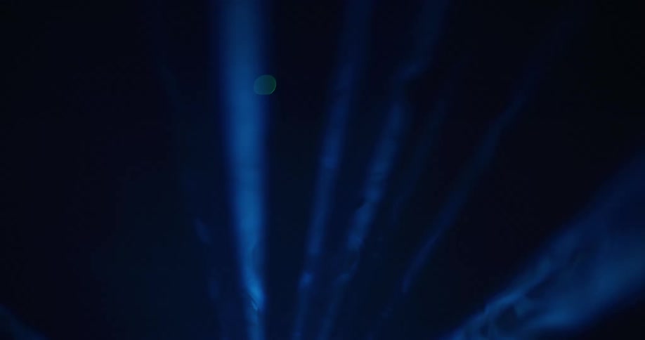 There is movement inside rays of blue light as they shine across the darkness