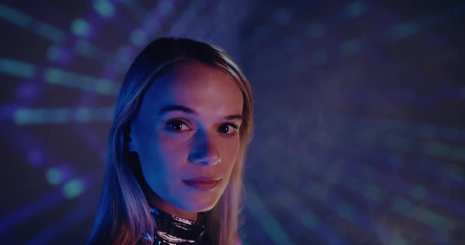 A woman stands in front of bright lights