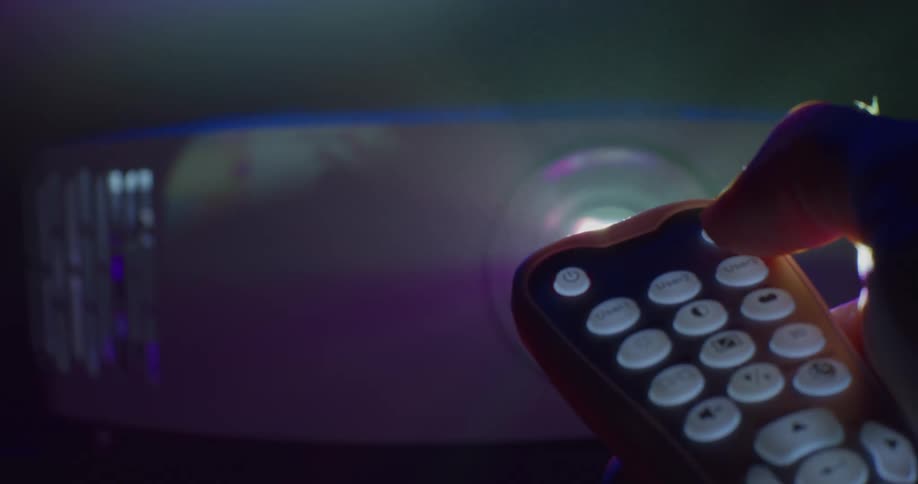 A man uses a remote to turn off a movie projector