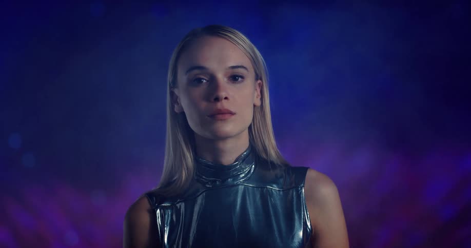 Colored lights fill background behind blonde woman wearing metallic fashion