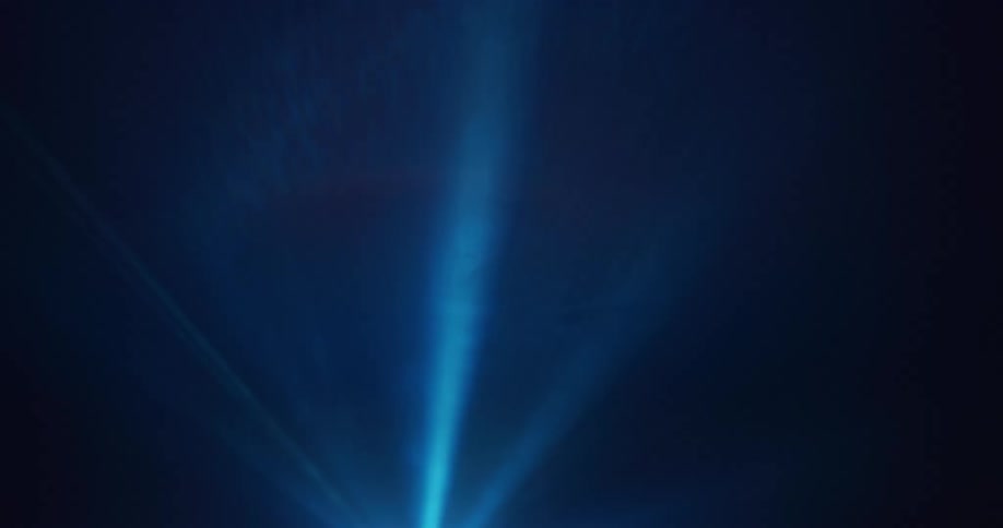 Neon blue lines of light are projected against a wall in a dim room