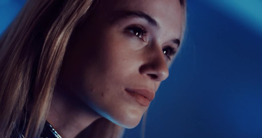 A woman looks up as she stands under bright lights