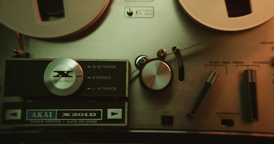 A person turning on a reel to reel tape player