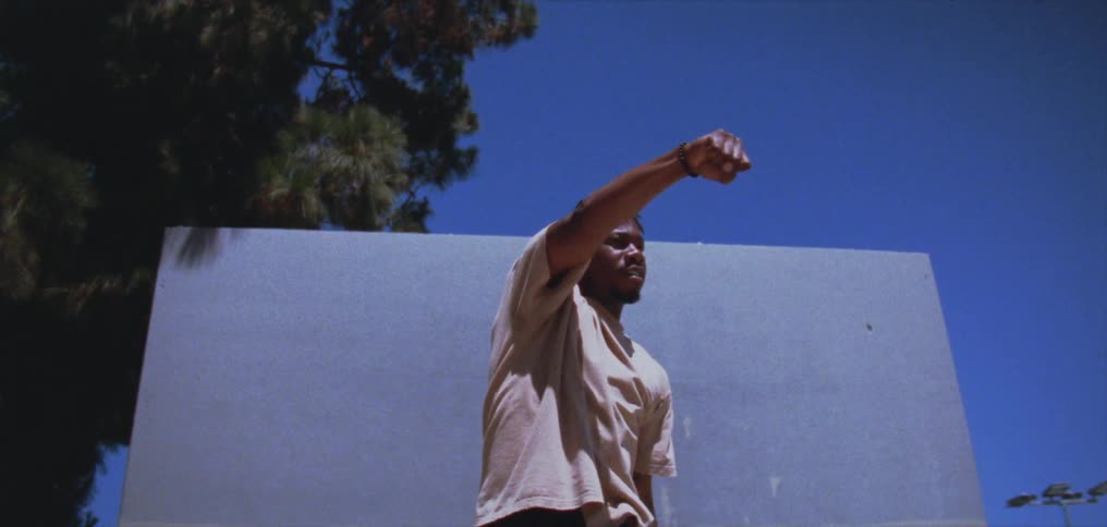 A man dances in front of a building wall