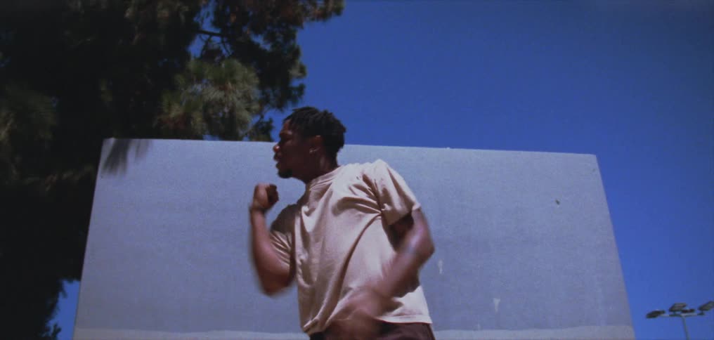 A young black man is dancing outside in the day time