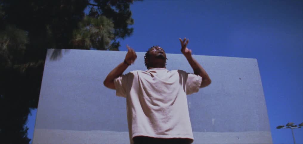 A man moves his arms up and down while dancing in front of a wall