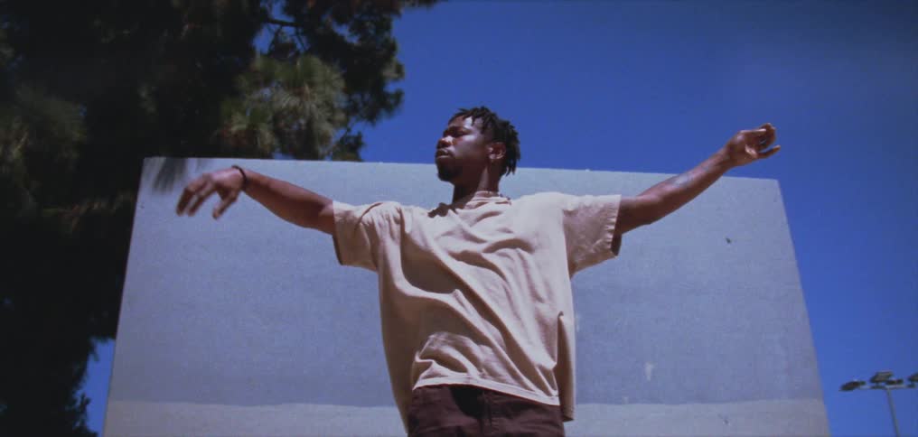 A young black man is moving his arms around outside