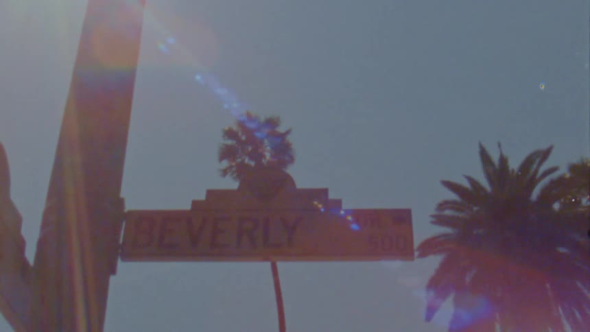 Sunlight shines on a street sign in beverly hills under a clear blue sky