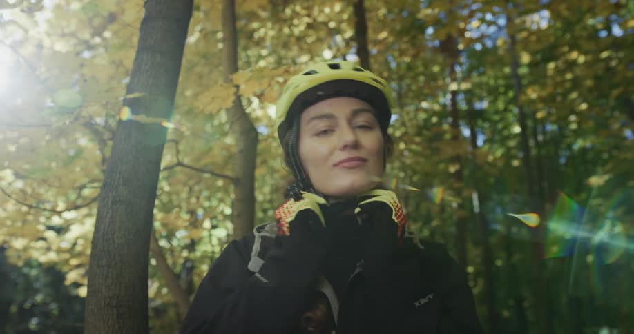 A young white woman puts a helmet on and rides her bike