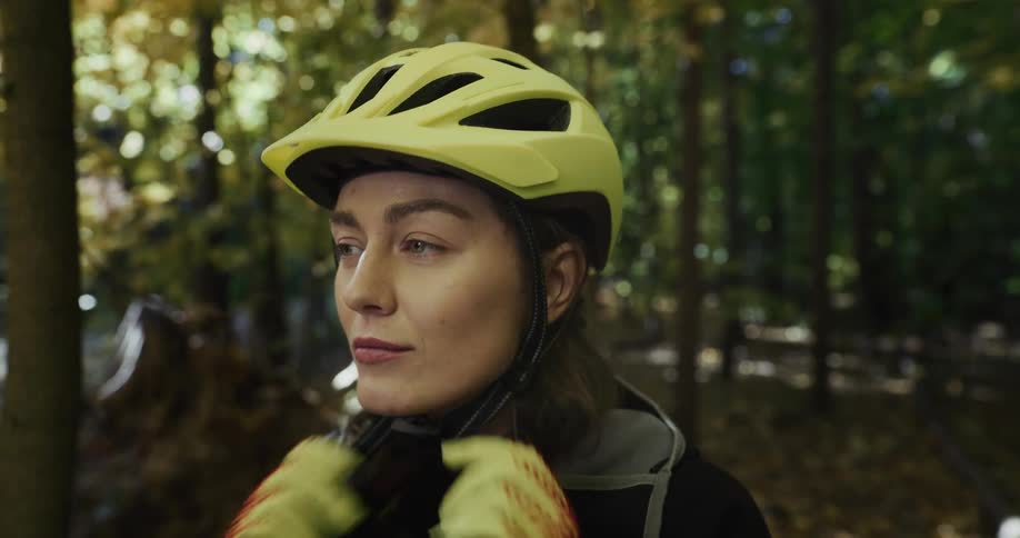 A woman is wearing a helmet and walking through a forest