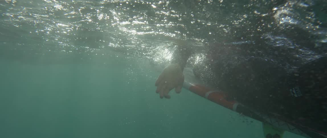 View of a surfer paddling as seen just below the waterline
