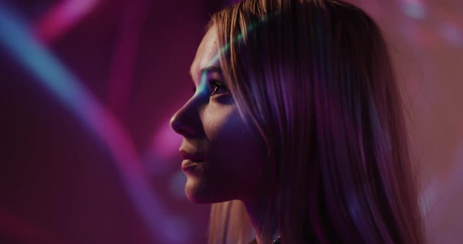 Colored light effects flow over face of blonde womans profile