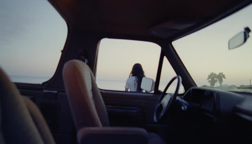 Woman with wavy hair white shirt and jeans gets out of pickup truck