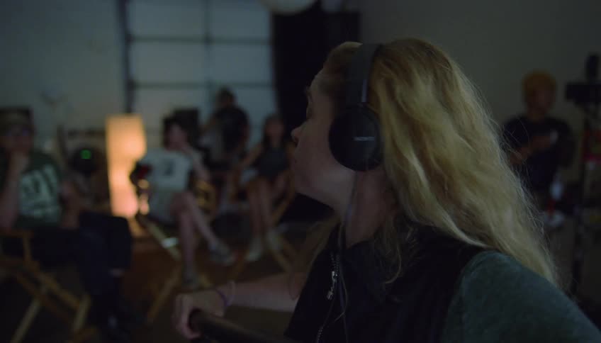 Boom operator working on a film set talks to the crew sitting behind her